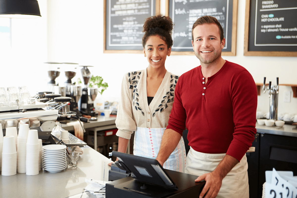 Male and female behind counter at coffee shop.